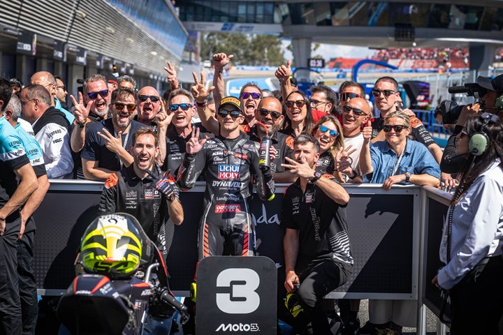 3位表彰台の「3」プラカードを背に、チームスタッフと喜びを分かち合うムニョス選手