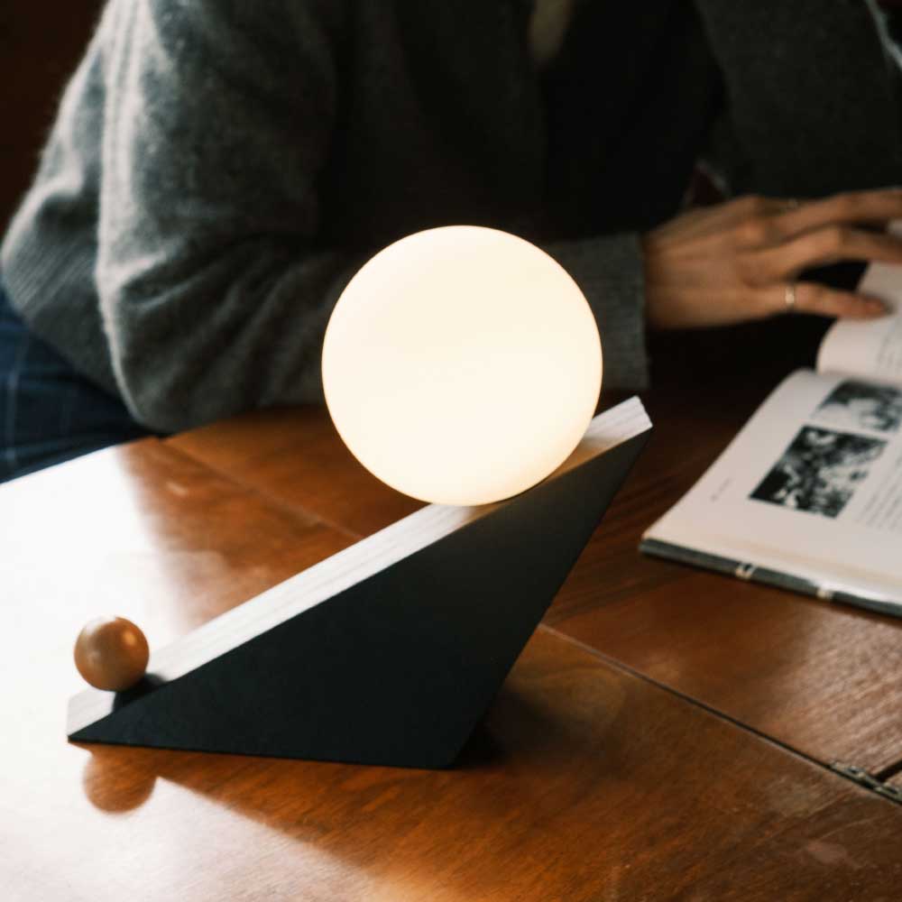 傾ける動作そのものがスイッチになる、オブジェのようなデザインの遊び心あるテーブルランプ