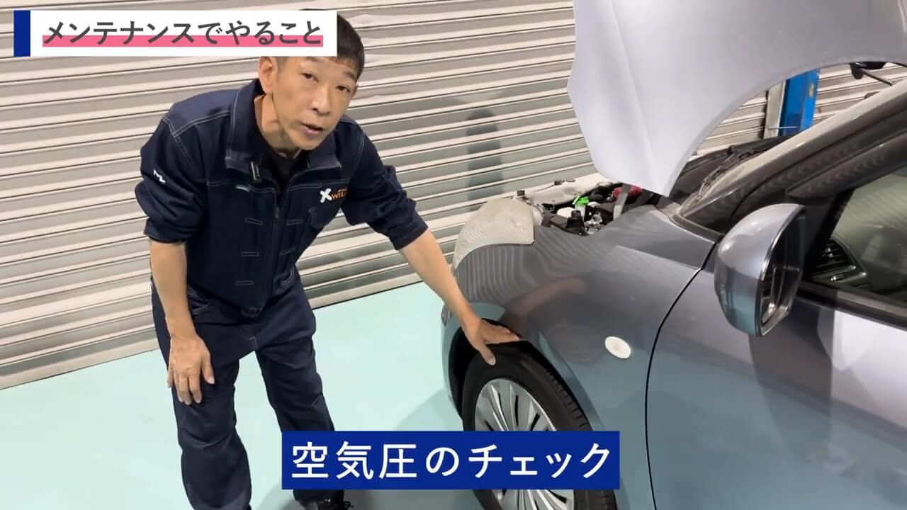 車のボンネットを開け、タイヤ周辺の確認を行うシーン