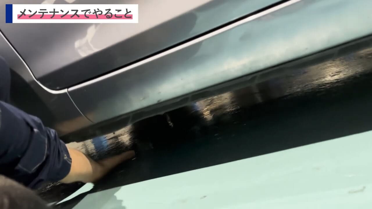 車両の下部を手で触れてシャーシ周辺の状態を確認しているシーン