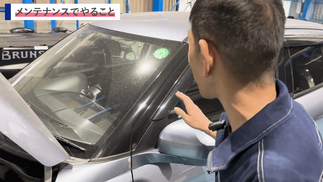 車のフロントガラスを指さしながら説明している場面で、ホコリや汚れが目立つ状態