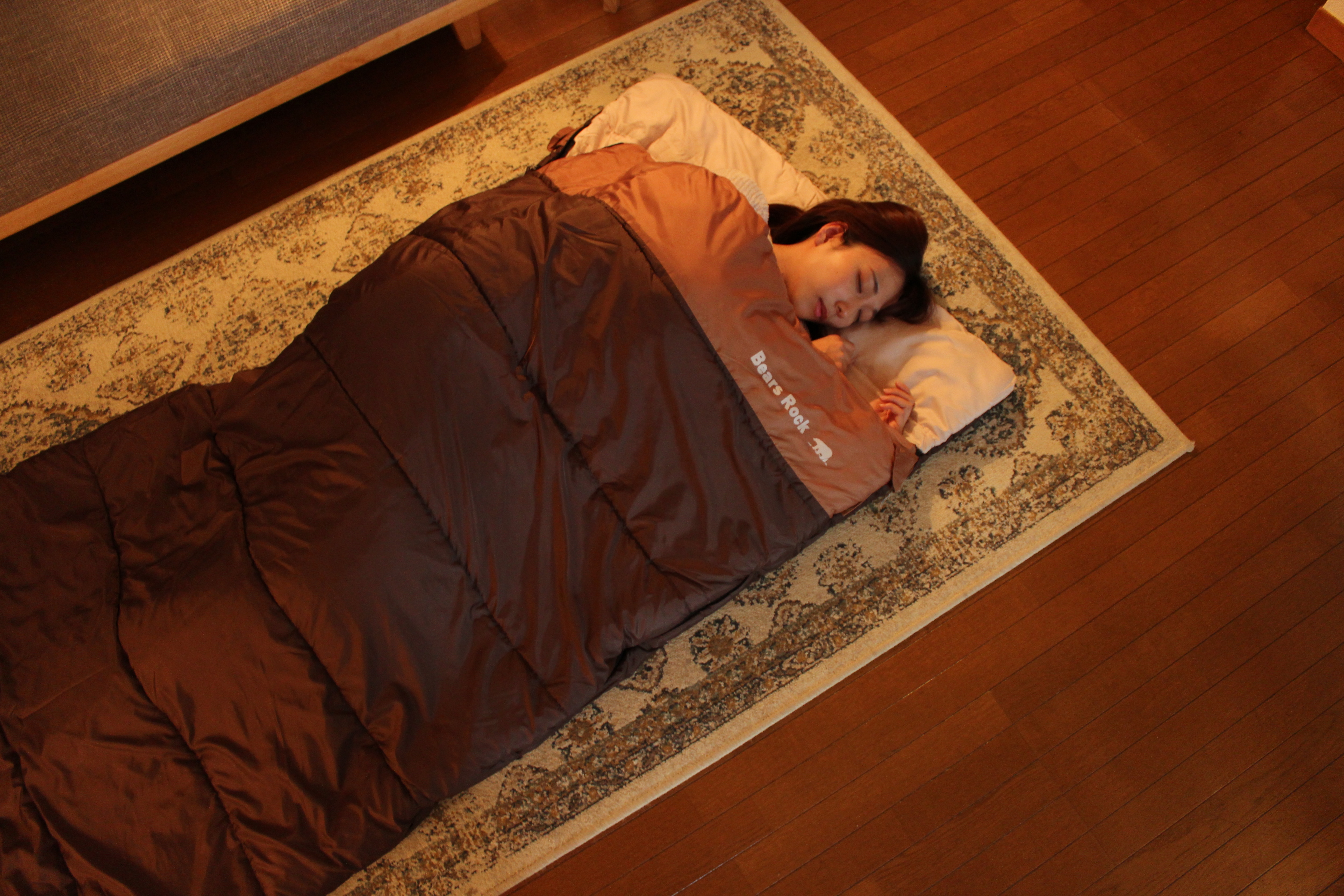 ねぶくろんに女性が入って眠っているイメージ写真です。ねぶくろんは袋状のお布団です。