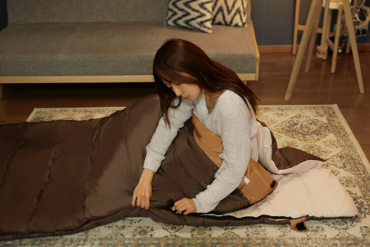ねぶくろんに女性が入って眠っているイメージ写真です。ねぶくろんは袋状のお布団です。