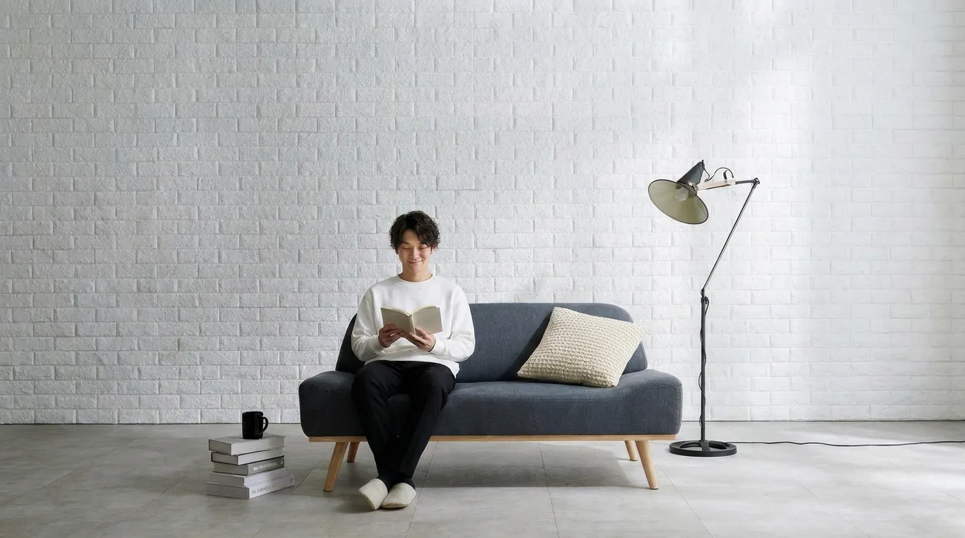 AIで作成したイメージ：グレーの2人掛けソファに座って本を読む様子
