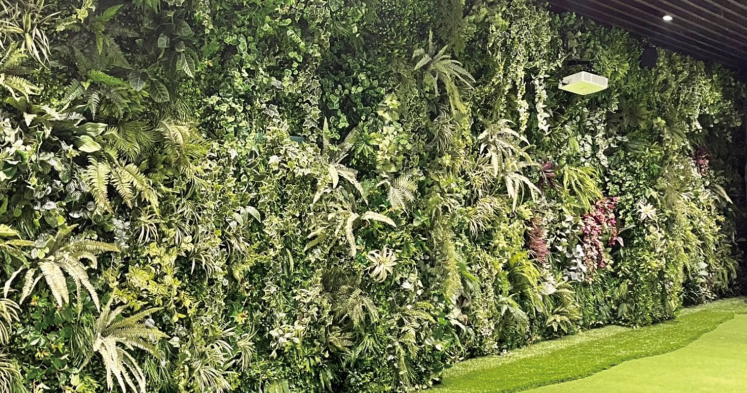 さまざまな種類の人工観葉植物やシダを壁面一面に敷き詰めた、大型壁面緑化（ウォールグリーン）フェイクグリーンの施工・設置例