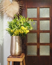 ゴールドのアルミニウム花器に黄色のフラワーアレンジメント