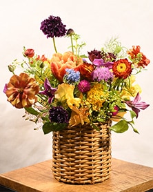 円筒のナチュラルなバスケットの器に艶やかなフラワーアレンジメント