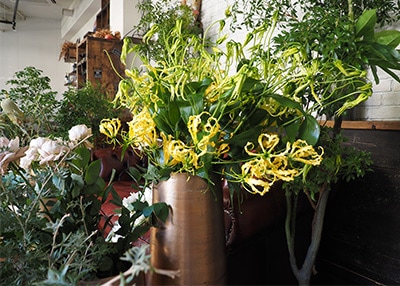 ゴールドのアルミニウム製フラワーベースに黄色い花が入っている使用イメージ