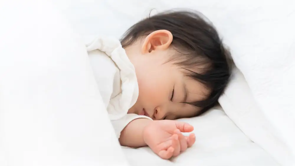 タオルケットを使って眠る幼児の画像