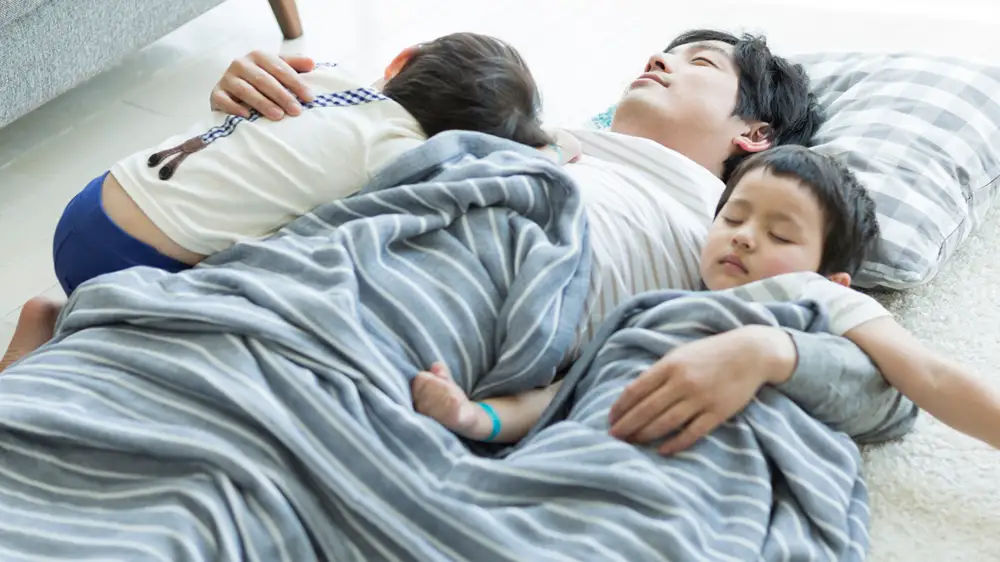 タオルケットを掛けて、お昼寝をする親子の画像
