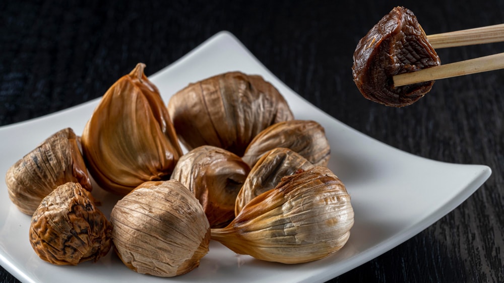 箸で持ち上げられる黒にんにくの画像