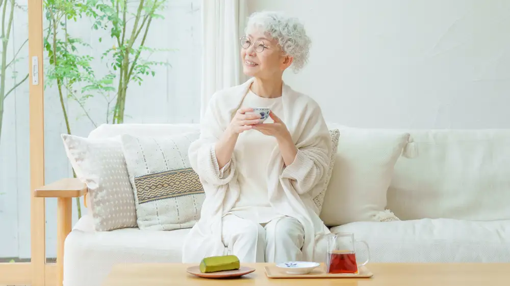 お茶を飲みながらゆっくりと過ごす一人暮らしの高齢女性の画像