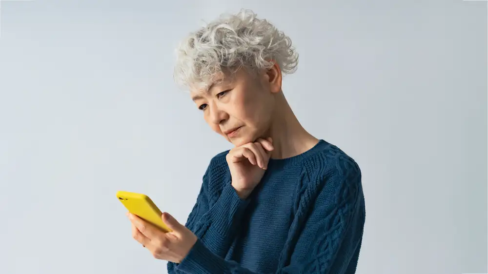 怪しい迷惑電話を疑う高齢女性の画像