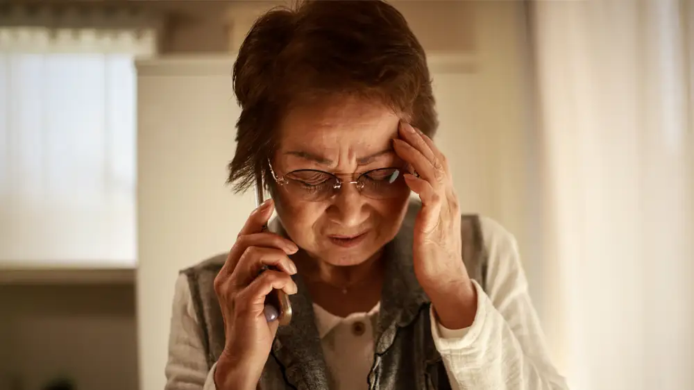 詐欺電話に惑わされる高齢女性の画像