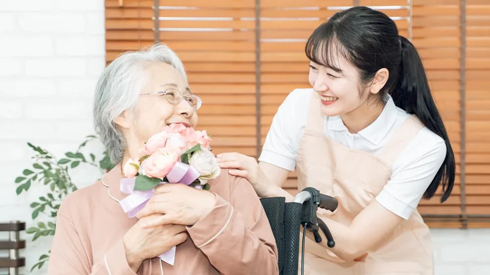 敬老の日にプレゼントを貰ったおばあちゃんと施設スタッフの画像