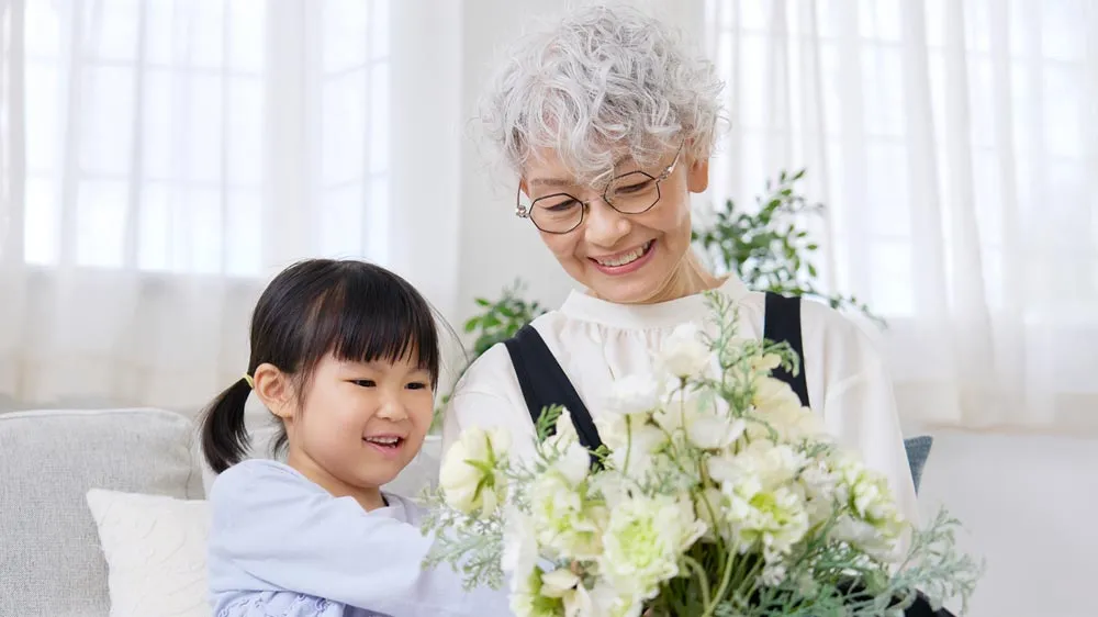 孫が祖母に花束をプレゼントする光景の画像