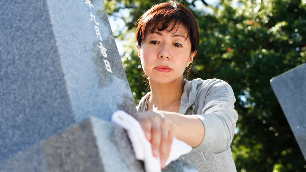 お墓を掃除する女性の画像