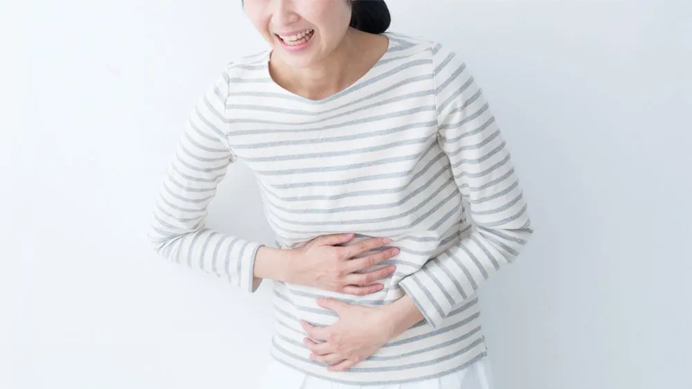 腹痛の症状が出ている女性の画像