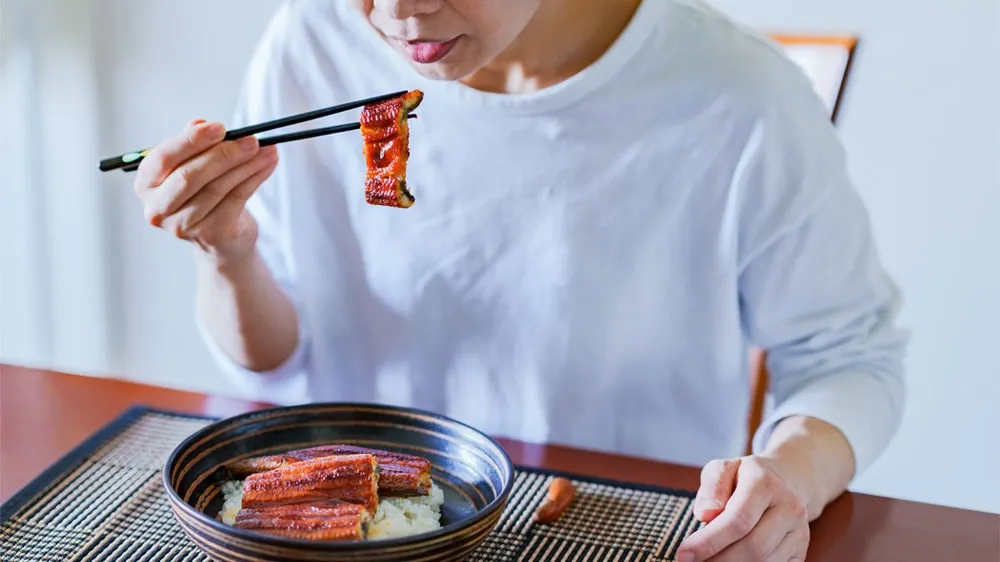 鰻丼を食べる女性の画像