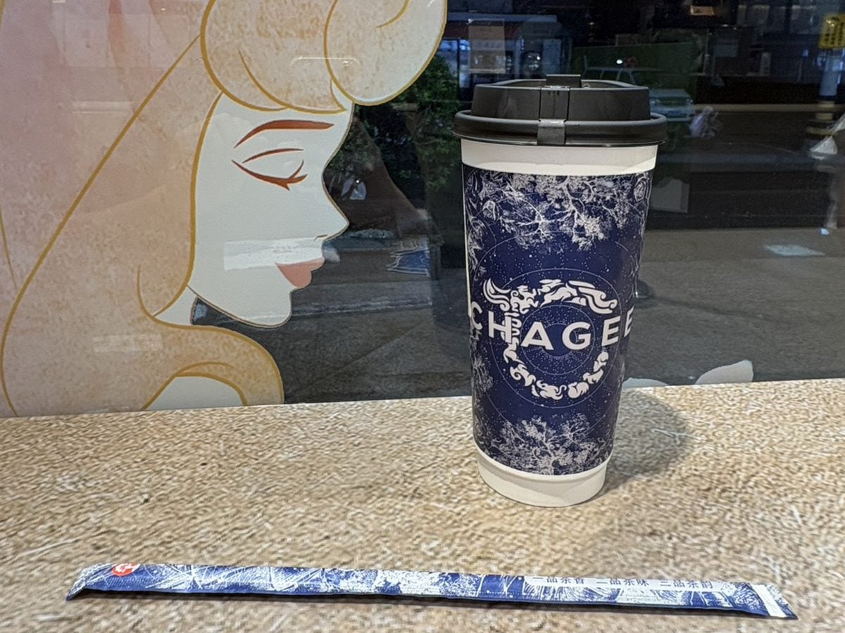 上海のCHAGEE店内のカウンターに置かれた、紺地に白の模様とCHAGEEのロゴが入ったカップと紙ストロー。窓にはディズニープリンセスのイラスト