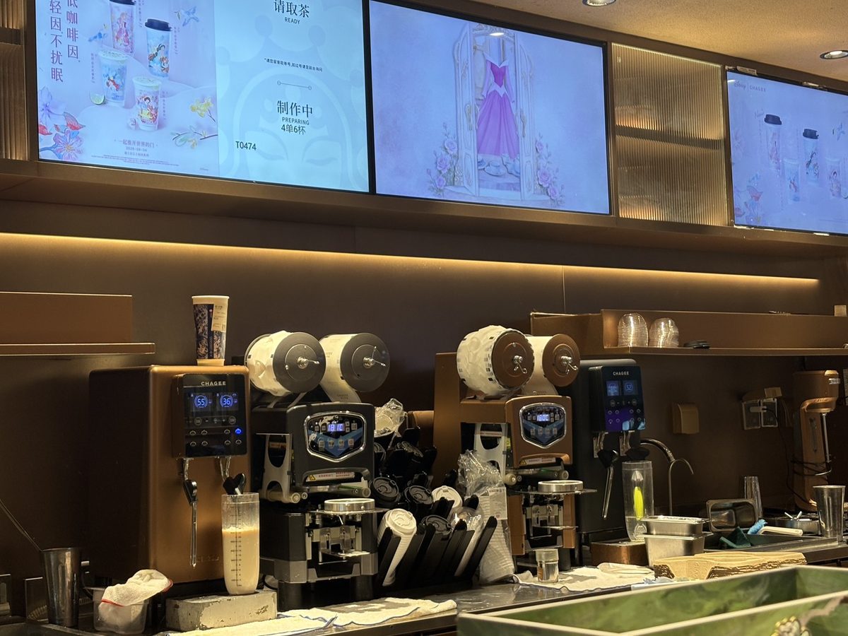 上海のCHAGEE店舗のカウンター。CHAGEEのロゴと数値の画面が付いた自動調飲機が2台と、カップのシール機、計量カップが並ぶ