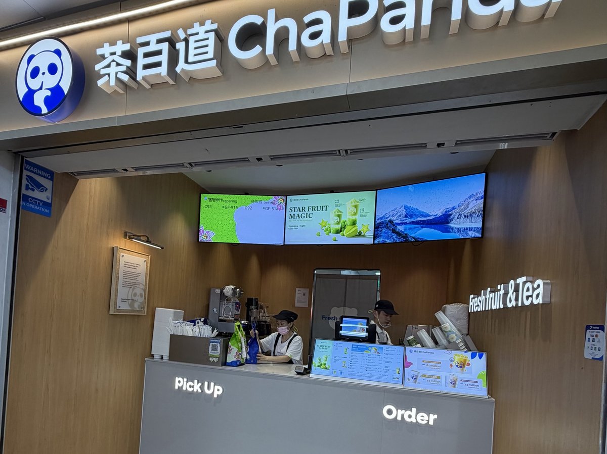 シンガポールの商業施設内にある茶百道（ChaPanda）の店舗。木目の壁に青いパンダのロゴと茶百道 ChaPandaの文字、カウンターにPick UpとOrderの表示、3枚のデジタルメニュー