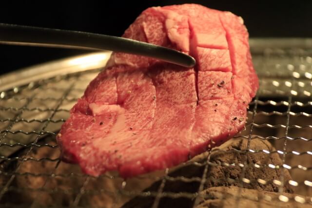 焼き網で調理される牛タンのステーキ