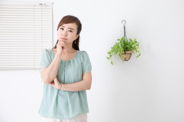 考え事をする女性と観葉植物