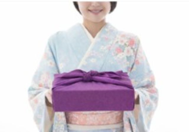 着物姿の女性が贈り物を手渡す