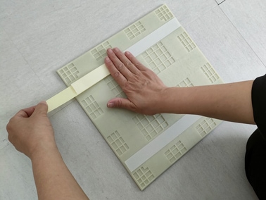 ファスナーテープをタイル裏面に貼る様子