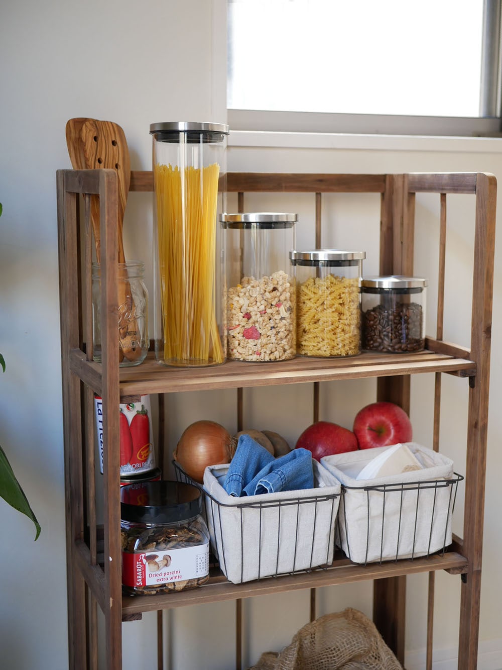 SALUS（セイラス）のスカンディックキャニスターが木製棚に整然と並び、バスケットやキッチンカートと共にキッチンの食品保存スペースを演出している様子