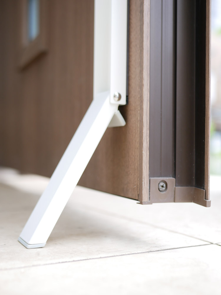 tower(YAMAZAKI)のスマートマグネット折り畳みドアストッパーが木製とガラスのドアに取り付けられている様子