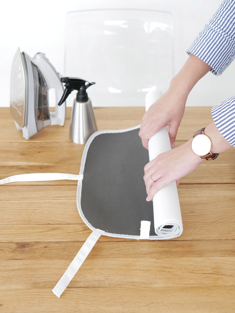 YAMAZAKIの【tower/タワー】くるくるアイロンマットがテーブルに広げられ、衣類のアイロン掛けに使用されている様子