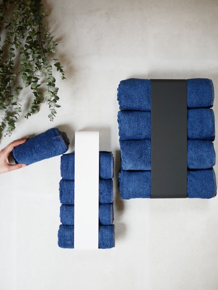 YAMAZAKIのスチール製【tower】マグネットバスタオルホルダーに約4枚のバスタオルが整然と掛けられている様子