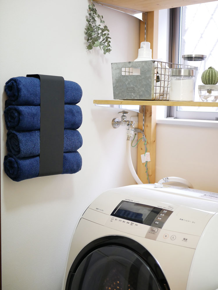 ヤマザキのスチール製マグネットバスタオルホルダーが壁に取り付けられ、4枚のバスタオルを掛けている様子