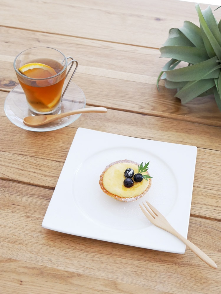 SALUSブランドの天然木製白カトラリーセット、130mmコーヒースプーンと175mmデザートフォークがプレートとソーサーと共にテーブルに配置されている