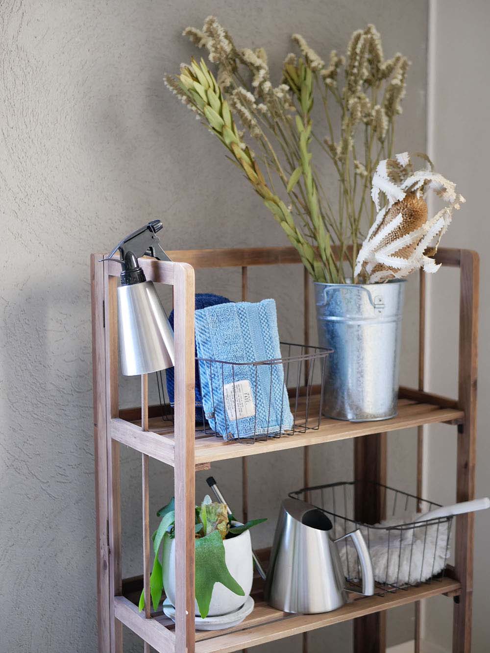 SALUSのステンレス製ミッテジョーロが籐の収納バスケットや鉢植えと共にキッチン棚に配置されている様子