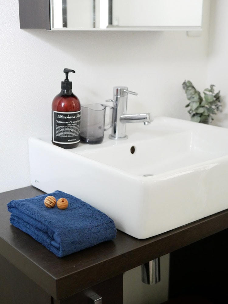 REST FOLKの綿100％プラシッドバスタオルとフェイスタオルが洗面台や浴室キャビネットとともに配置された浴室の様子