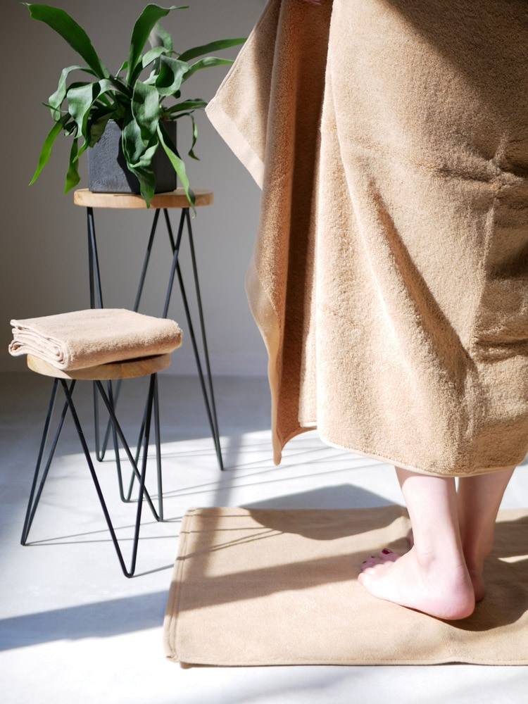 REST FOLKの綿100％プラシッドフェイスタオルとバスタオルが木製フローリングの上に敷かれている