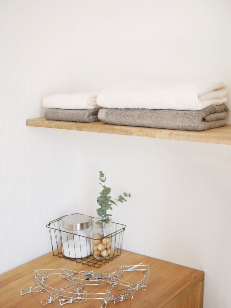 レストフォークのプラシッド柄バスタオルとフェイスタオルが木製の棚に美しく並べられている様子