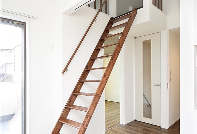 アパートのリビングに掛かる、ブラウン塗装の木製ロフト階段・ワイドステップのお部屋実例。
