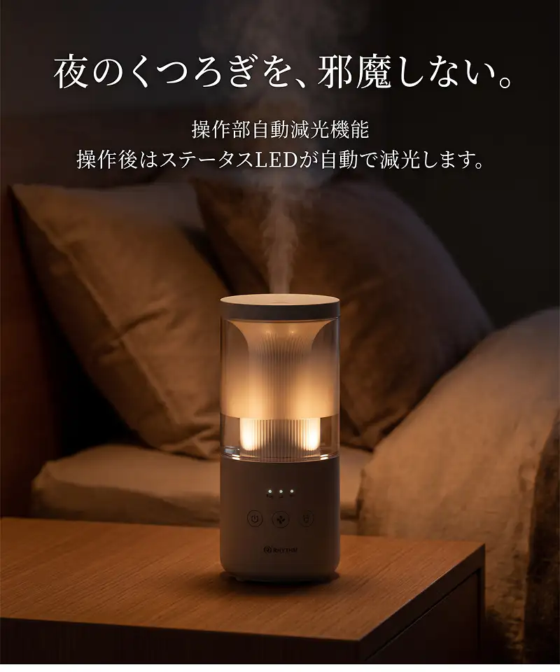 暗い寝室のベッドサイドに置かれた RHYTHM MIST Mini 2 プールレス加湿器。プールレス構造でミストと暖かな光を放出し、夜のくつろぎを邪魔しない操作部自動減光機能を紹介。