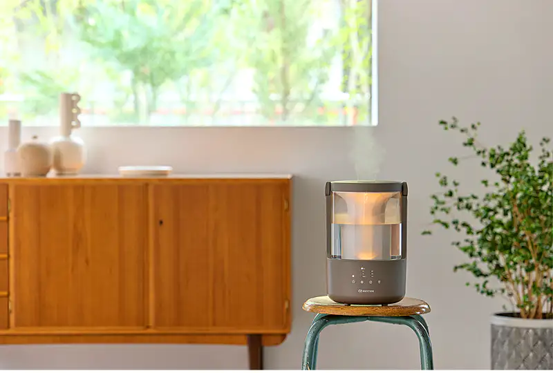 RHYTHM MIST 250加湿器のウォームグレーモデル。ミッドセンチュリー風の家具があるリビングに置かれ、部屋に溶け込むデザイン。