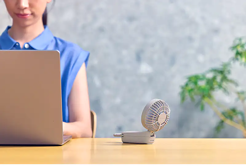 携帯扇風機 Silky Wind Mobile 4をデスクファンとして使用する女性のイメージ。