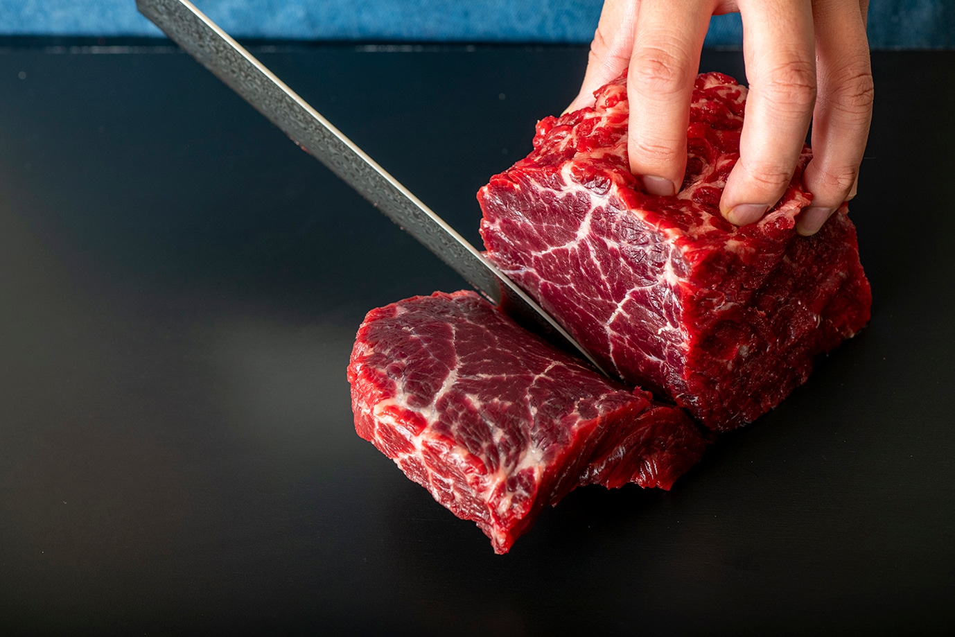 職人が厳選した鯨肉を包丁で丁寧に仕込む様子 — いさな家の熟成鯨肉