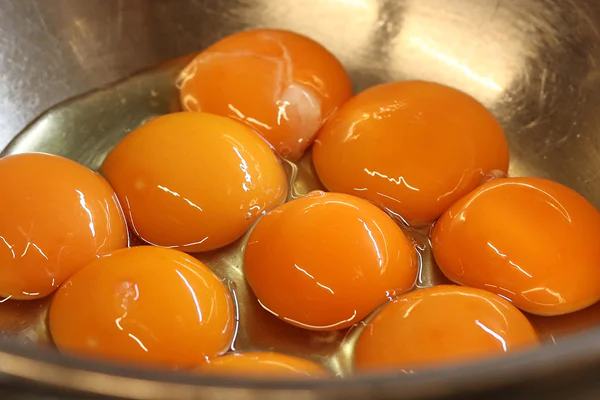 ボウルに割り入れられたたくさんの卵黄の写真