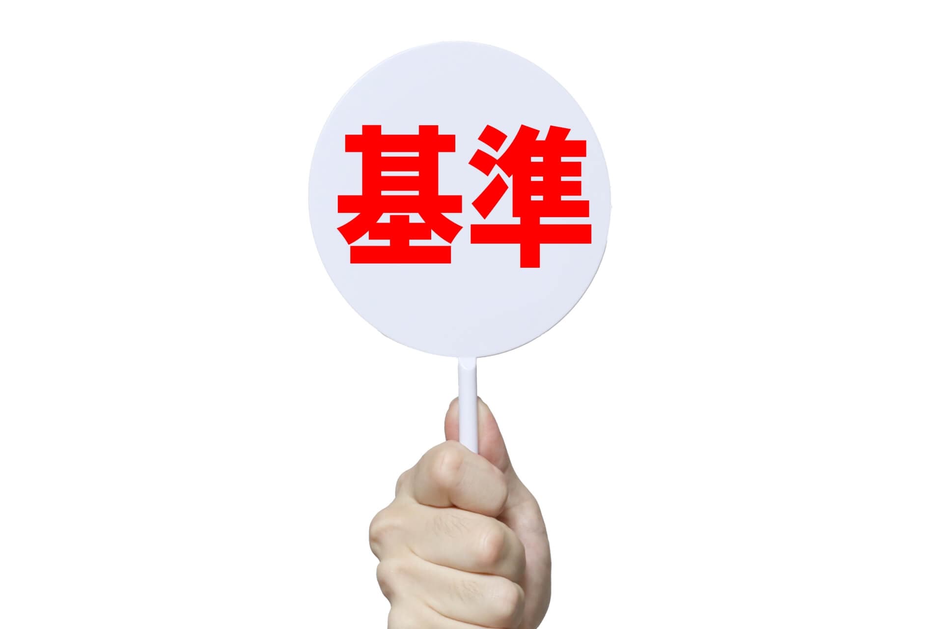 基準と書かれた白い札を持つ手
