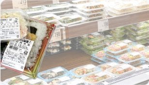 食品売場に並ぶパック惣菜と、貼付された原材料名・栄養成分表示ラベル