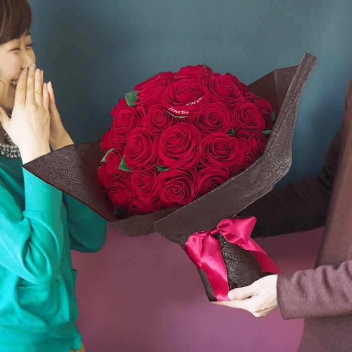 赤バラのプレゼントに喜ぶ女性