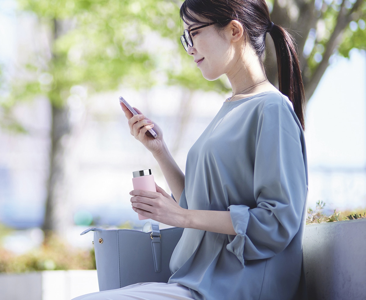 使用シーン　スマホと同じくらいコンパクトなサイズのボトルを手にベンチで休憩